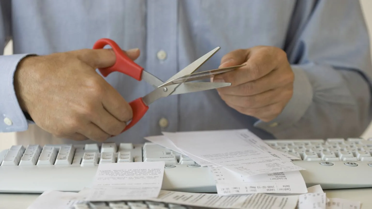Image: Getty Images Man's hands cutting up credit card.