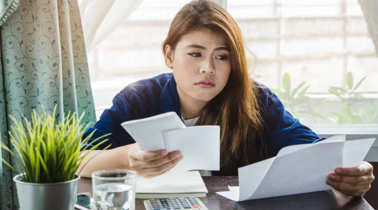 shutterstock_StressedHomebuyer738 A young woman frustrated while looking at bills.