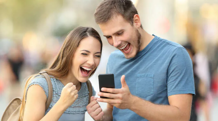 Auction_Winners_738_shutterstock_725511226 Young couple looking excited at their phone.