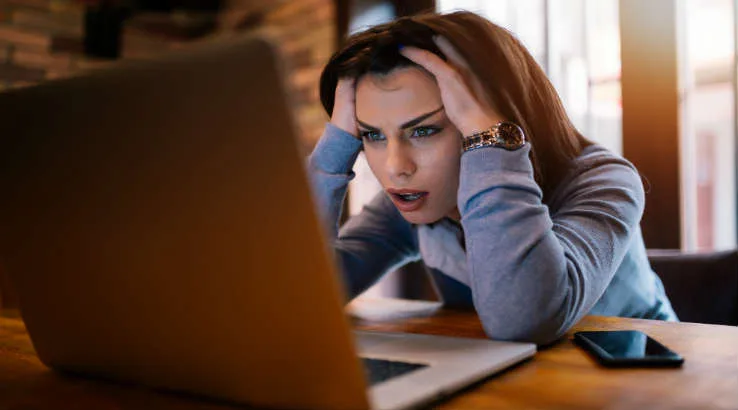 Upset738shutterstock_1047662398 Woman at computer looking stressed.