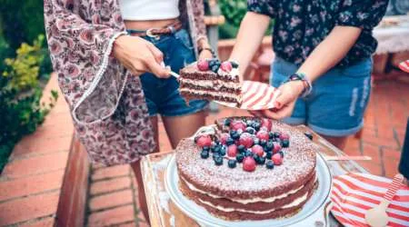 Midsection Of Woman Giving Cake Slice To Friend At Backyard Midsection Of Woman Giving Cake Slice To Friend At Backyard
