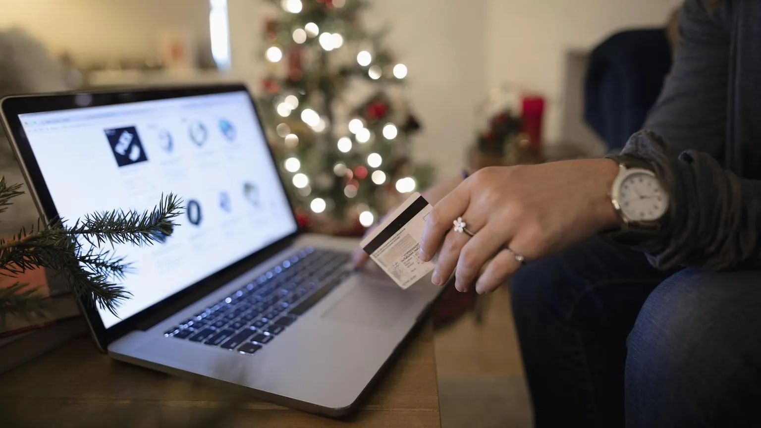 Image: Getty Images Person holding credit card with laptop with Christmas tree in the background