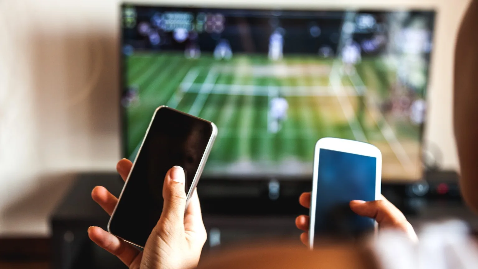 Image: Getty Images Friends using mobile phone during a tennis match on the TV.