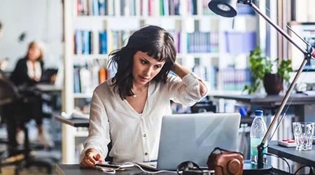 Businesswoman looking at laptop while sitting in office Businesswoman looking at laptop while sitting in office