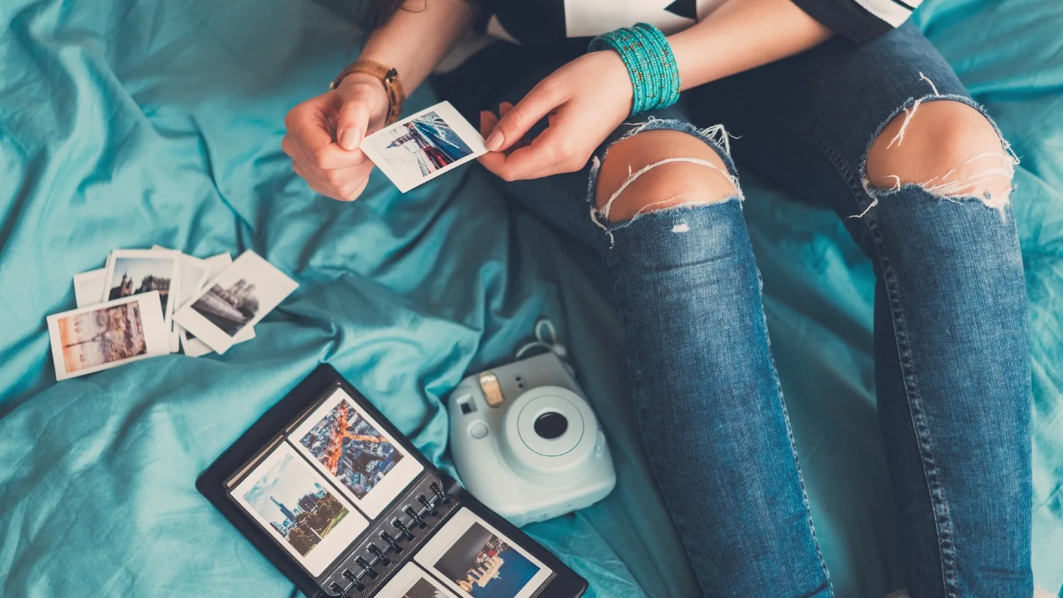 Image: Getty Images Female sitting on her bed sorting her travel photos.