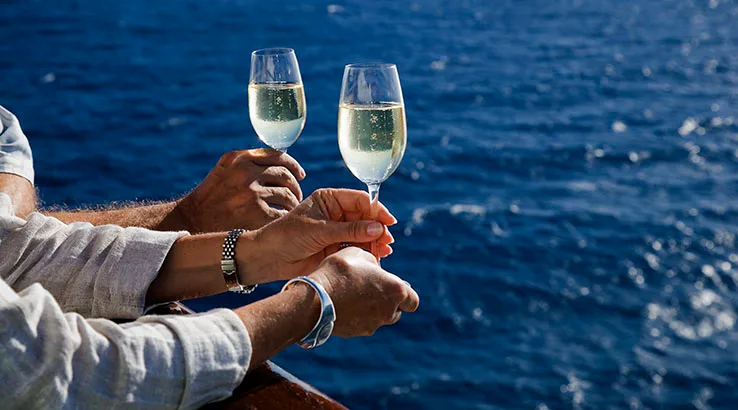 Hands holding champagne glass on cruise ship