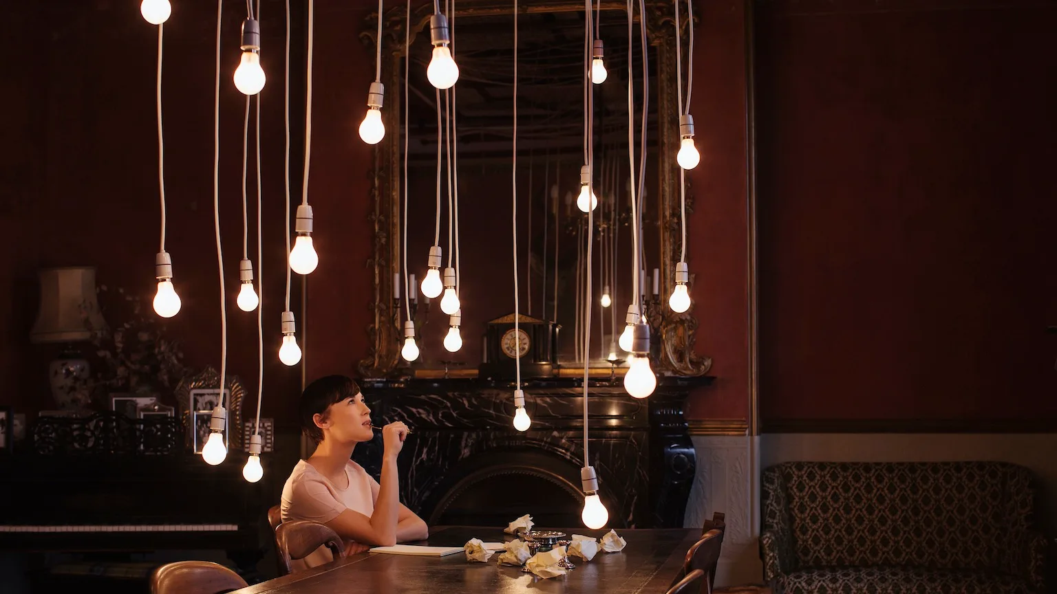 Image: Getty Images Woman sitting at table with hanging lightbulbs
