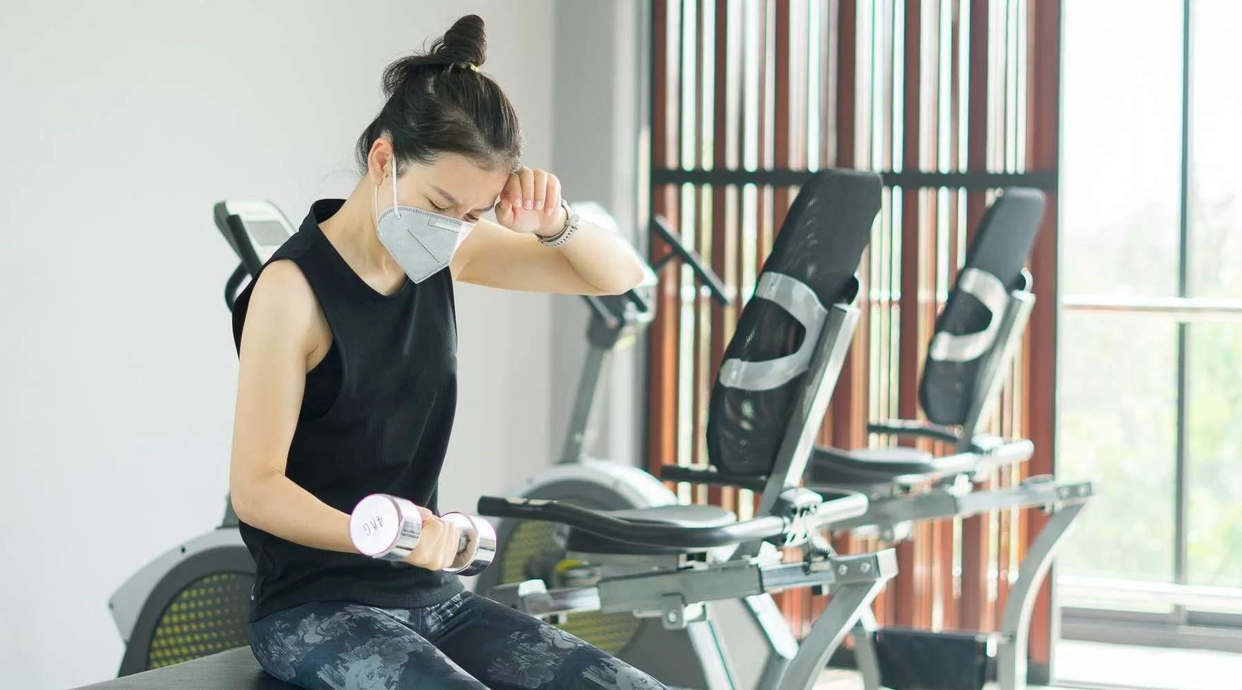 asian sporty female wearing anti pollution mask and workout weight training for keep fit with dumbbell at gym asian sporty female wearing anti pollution mask and workout weight training for keep fit with dumbbell at gym