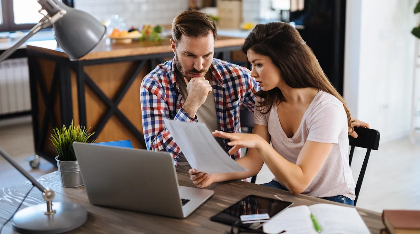 Frustrated couple checking bills at home using laptop Frustrated couple checking bills at home using laptop