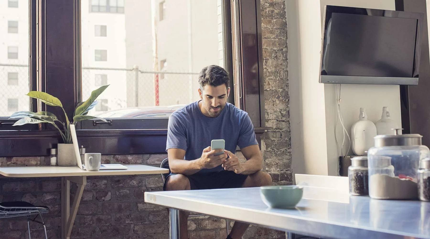 Young man standing in kitchen using smart phone Young man standing in kitchen using smart phone