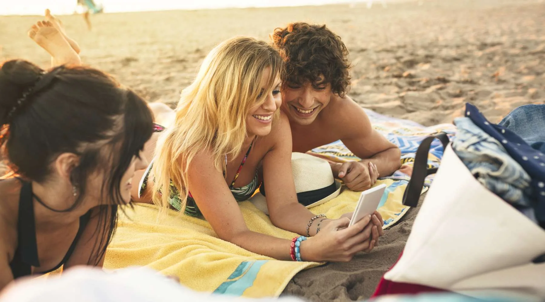 Smiling young man and woman sharing cell phone on the beach Smiling young man and woman sharing cell phone on the beach