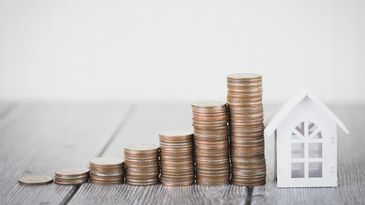 Image: Getty Images Stacks of coins next to a little white house