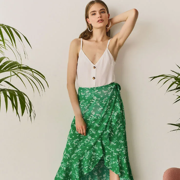 Blond model posing with a white shirt and a green skirt