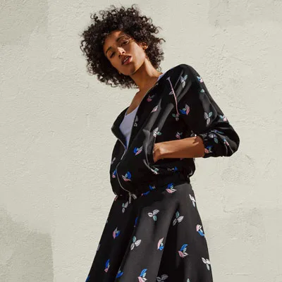 Brunette woman posing with a black floral dress
