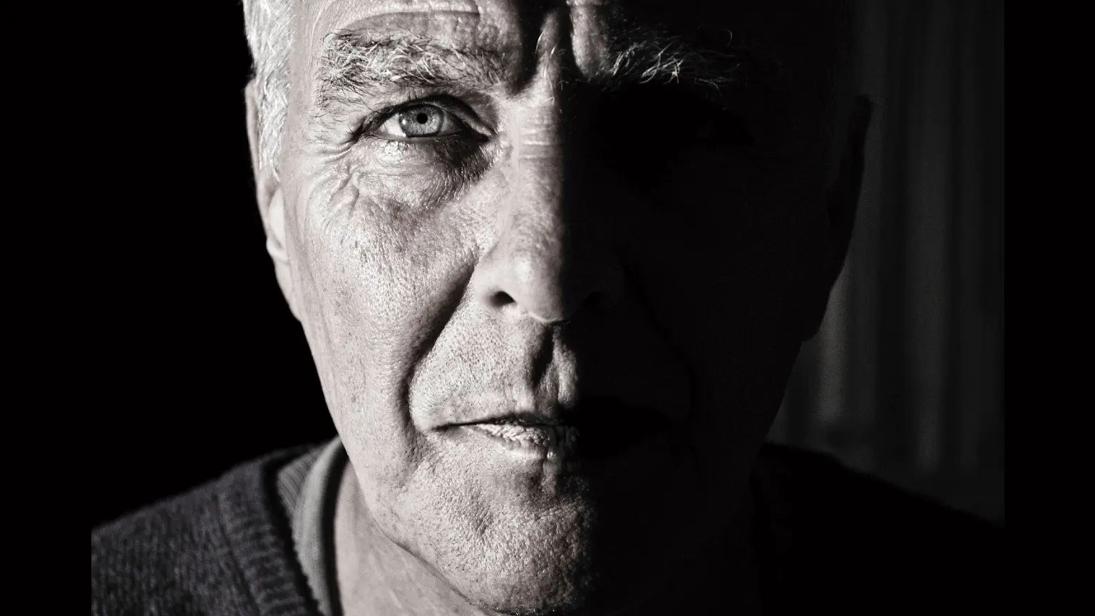 Image: Shutterstock Face of an old man with a dark shadow on half of the face