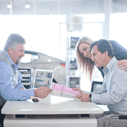 Image: Getty Images Car salesman and couple looking at contract in showroom