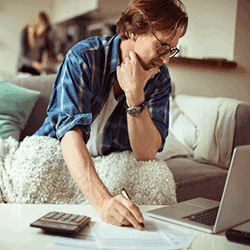 Image: Getty Images Man worried about bills, looking at laptop