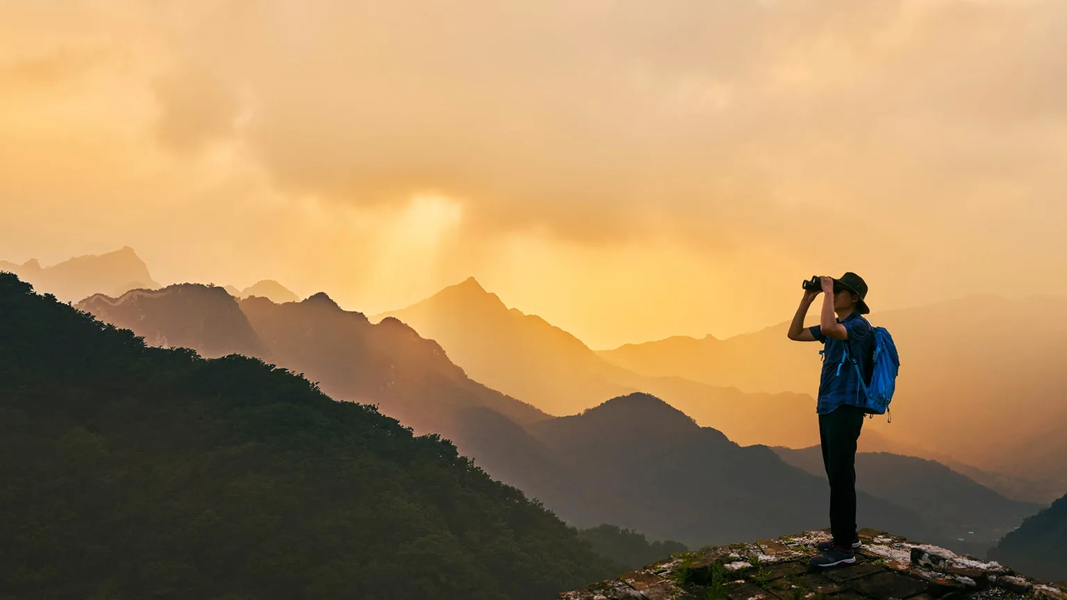 Image: Getty Images man on a mountain top with binocular