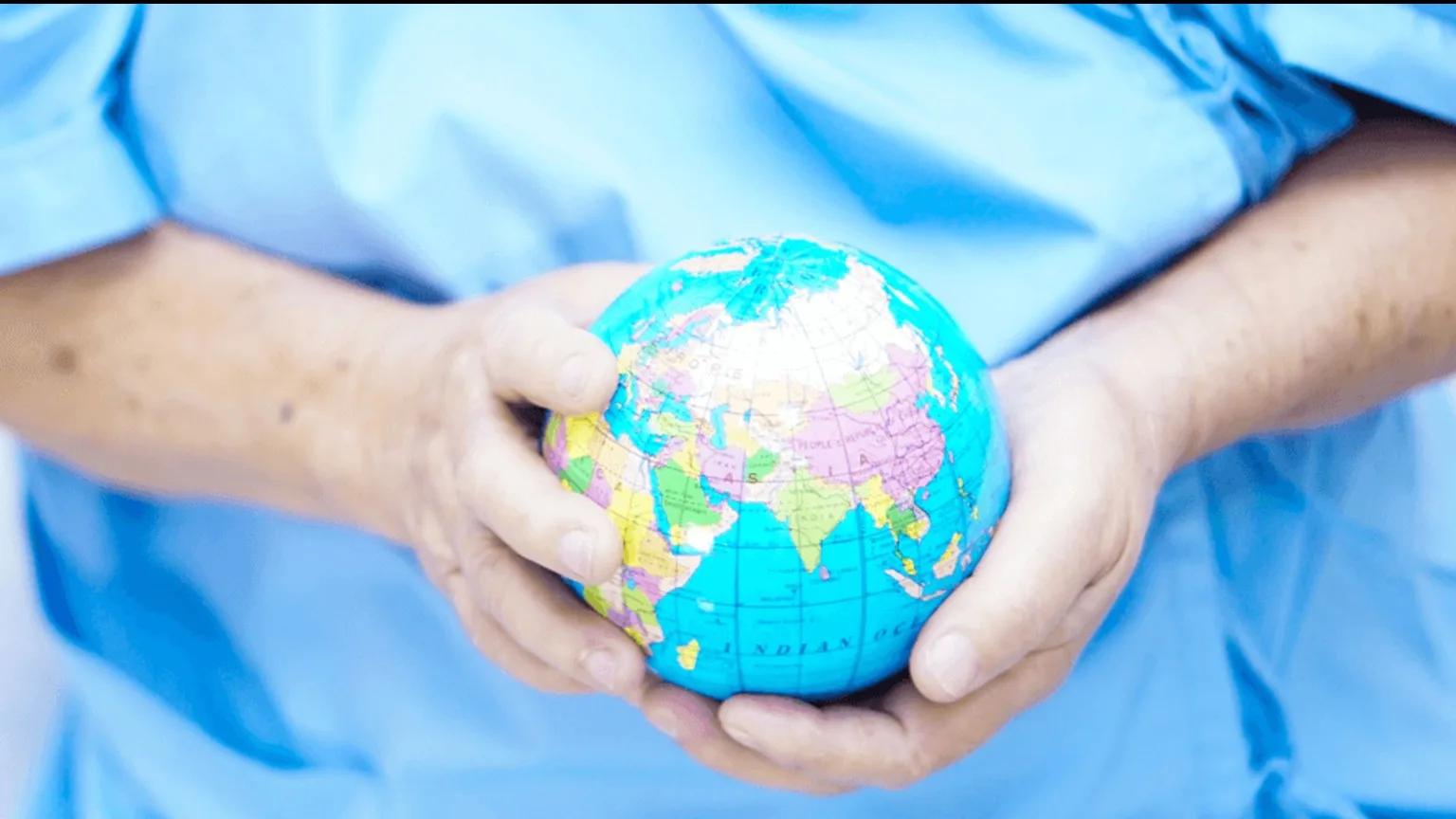 Image: Shutterstock Man in hospital blue clothes with a globe in hand
