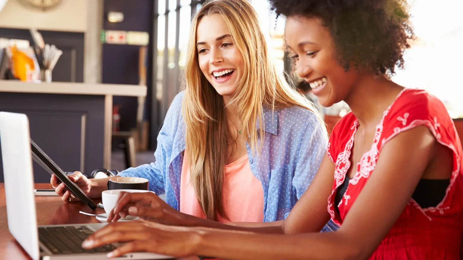 Image: Shutterstock Two ladies smiling and looking on a computer