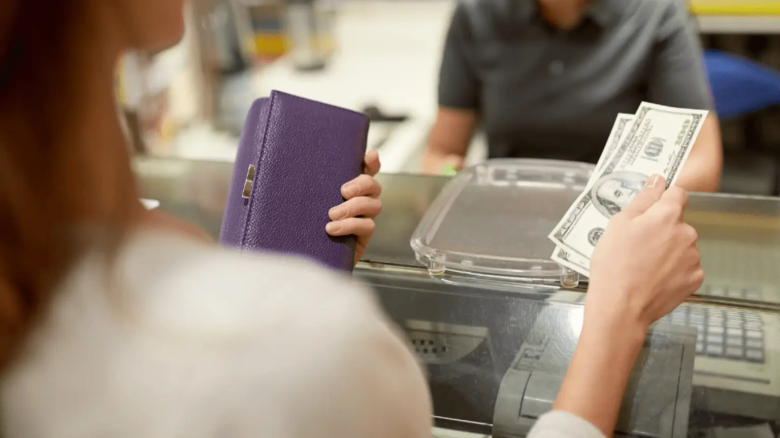Image: Shutterstock A woman paying with dollar bills over a counter