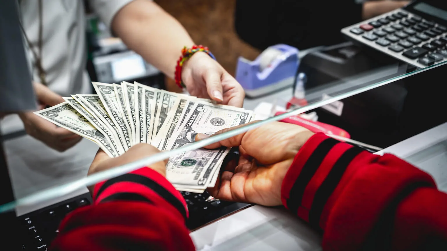 Image: Getty Images Hands receiving cash at bank teller