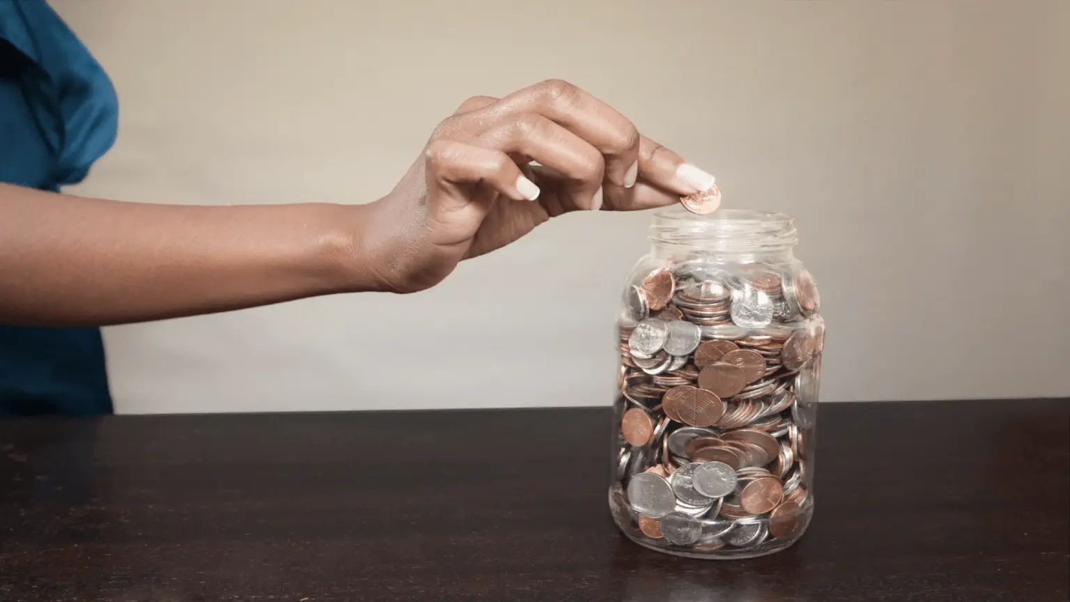 Image: Getty Images Person putting a coin in a jar
