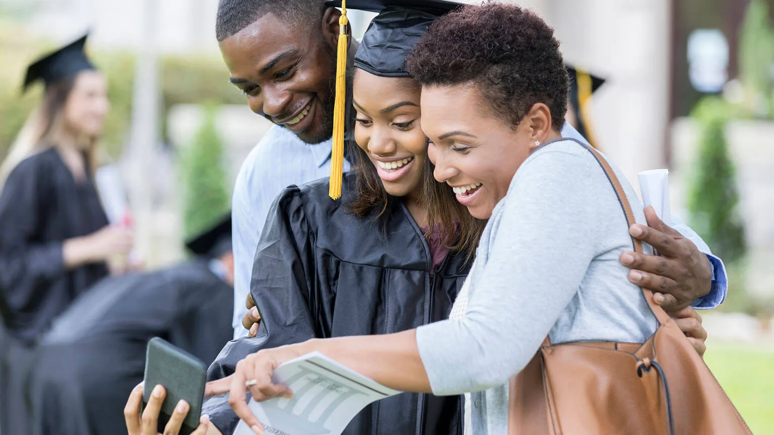 Image: Getty Images College graduate taking selfie with parents