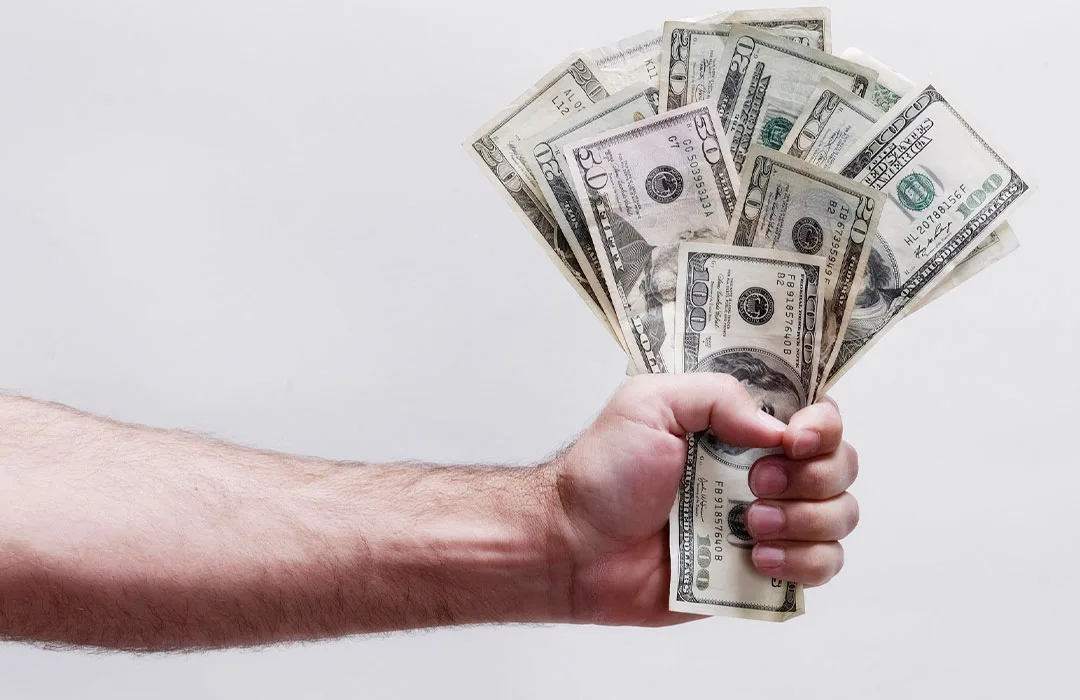 Image: Getty Images Picture of a man handing over a wad of cash
