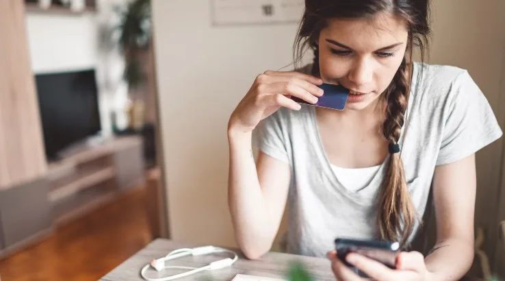 Image: Getty Images Young woman bitting her bank card