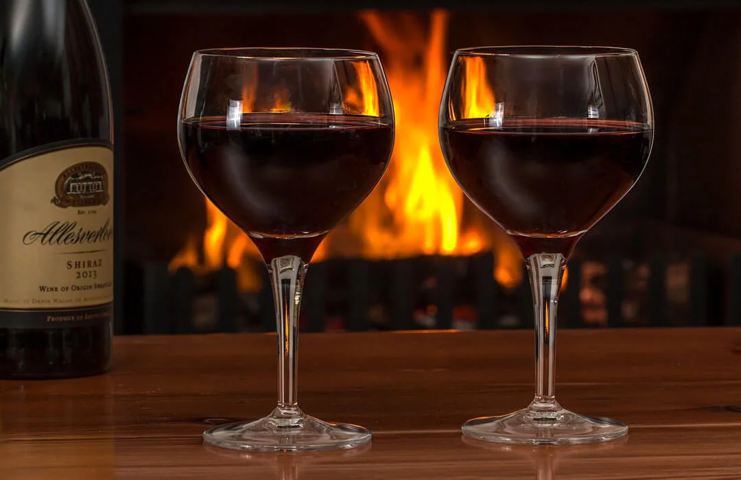 Image: Getty Images Two glasses of wine in front of fireplace