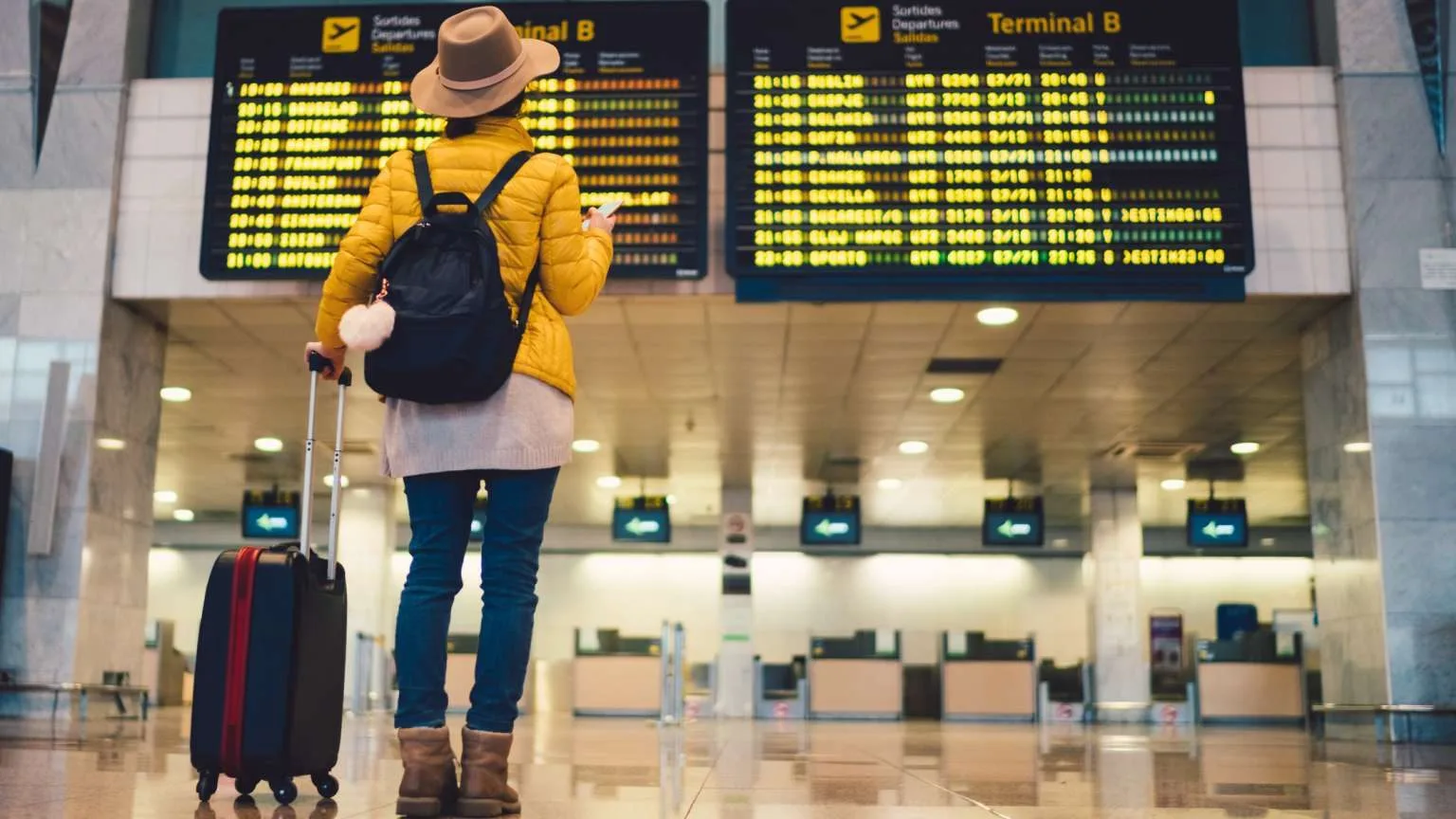 Image: Getty Images Young woman at the airport in Barcelona checking for the flight schedule