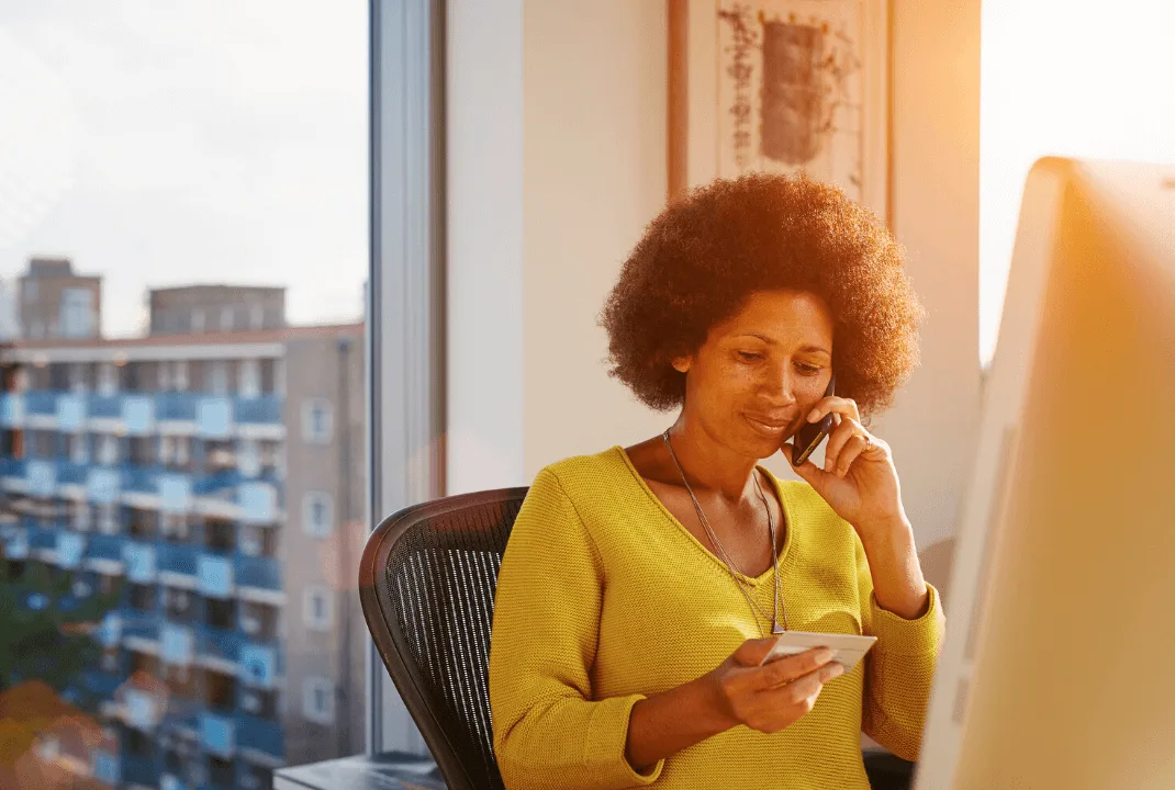 Image: Getty Images Woman looking at a card infront of a computer