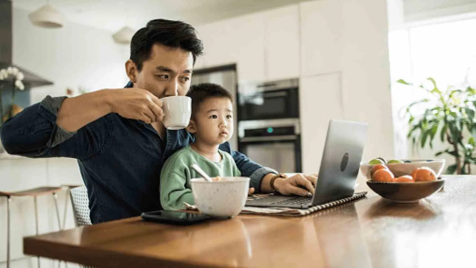 Image: Getty Images Father working from home with young son at kitchen table