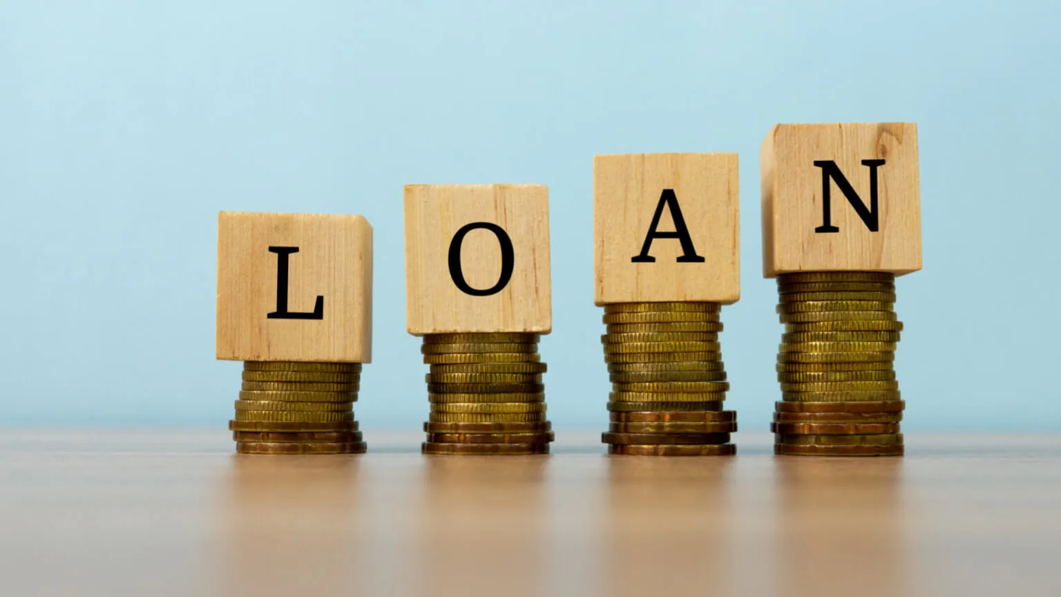Image: Getty Images scrabble pieces spelling the word loan, stacked on pennies