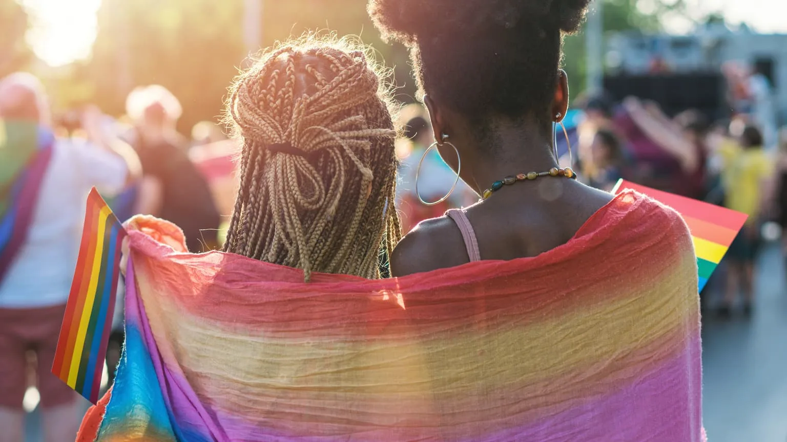 Image: Getty Images Young female couple wrapped in rainbow scarf