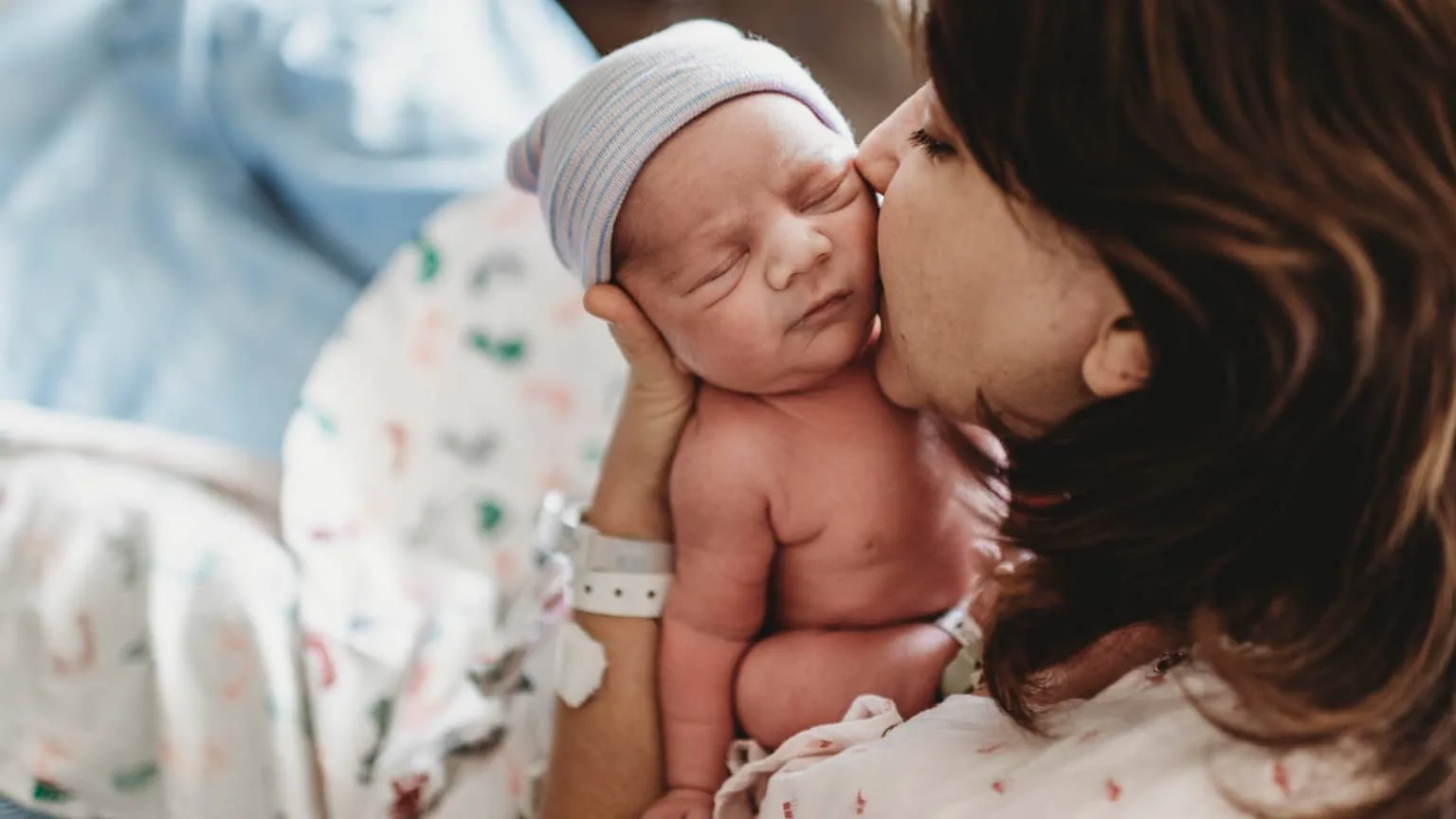 Image: Getty Images a mother kissing her newborn baby while still in the hospital bed