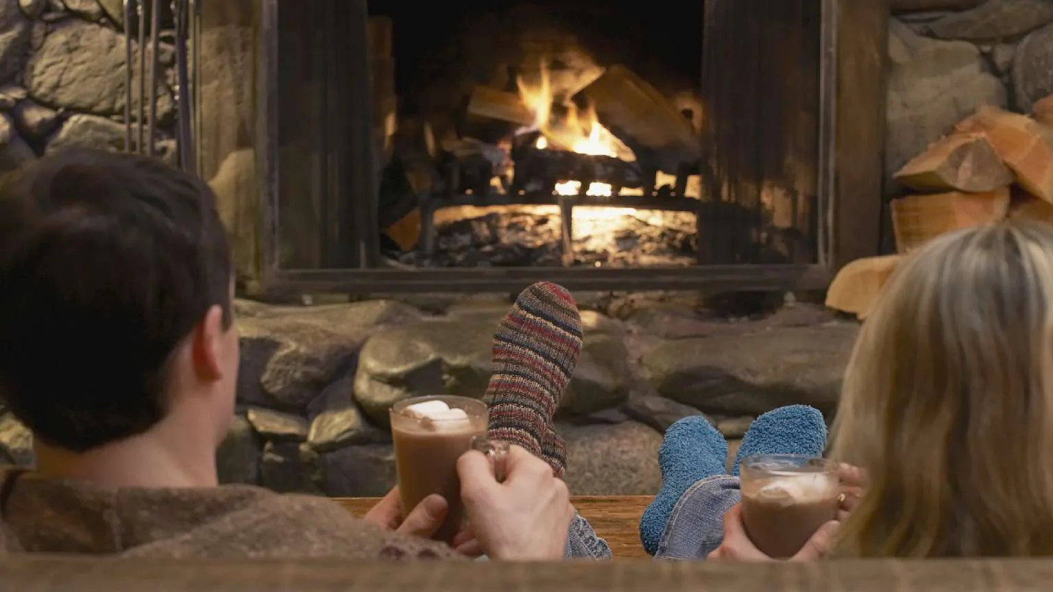 Image: Getty Images Couple relaxing in front of a roaring fire in a winter cabin.