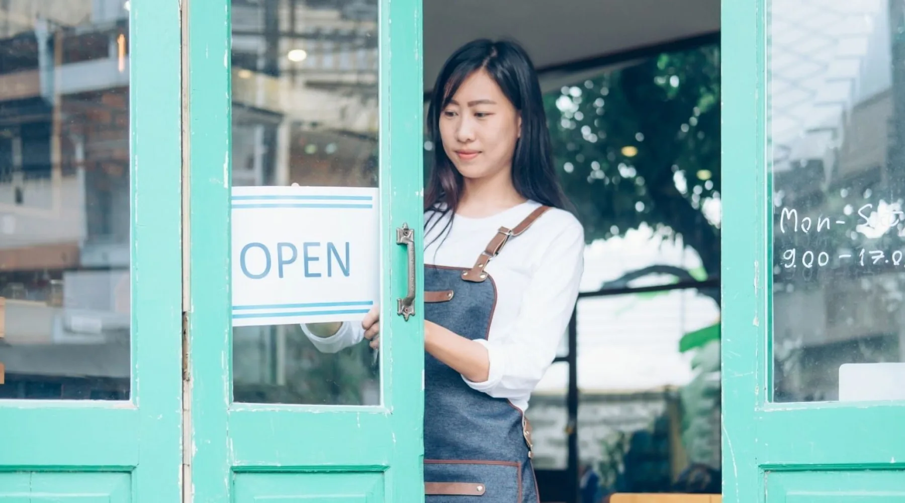 WomanWithOpenBusinessSign_Canva_1800x1000 WomanWithOpenBusinessSign_Canva_1800x1000