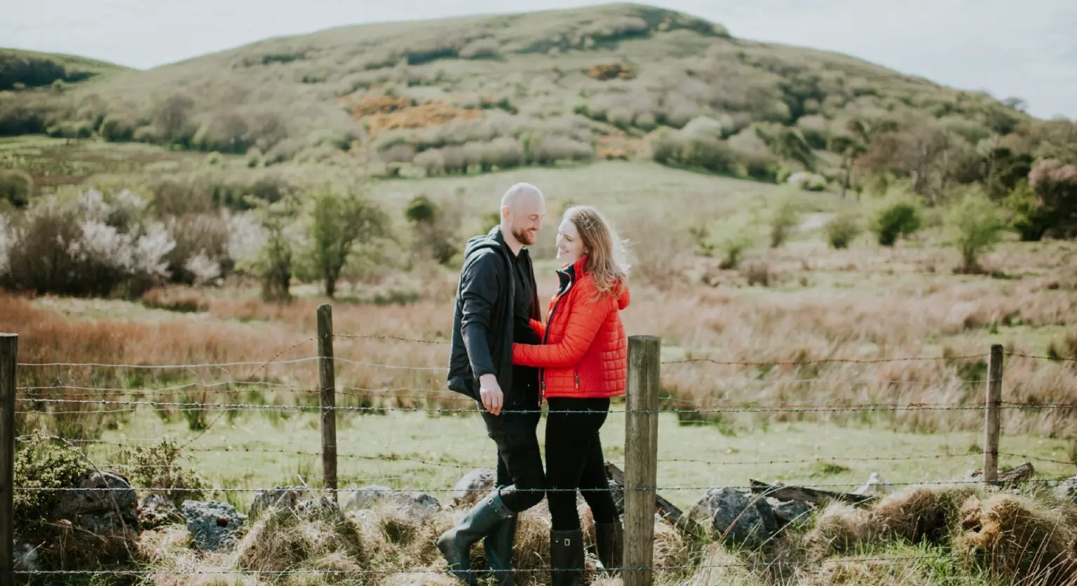 Image: Getty Images Young couple embrace in countryside.