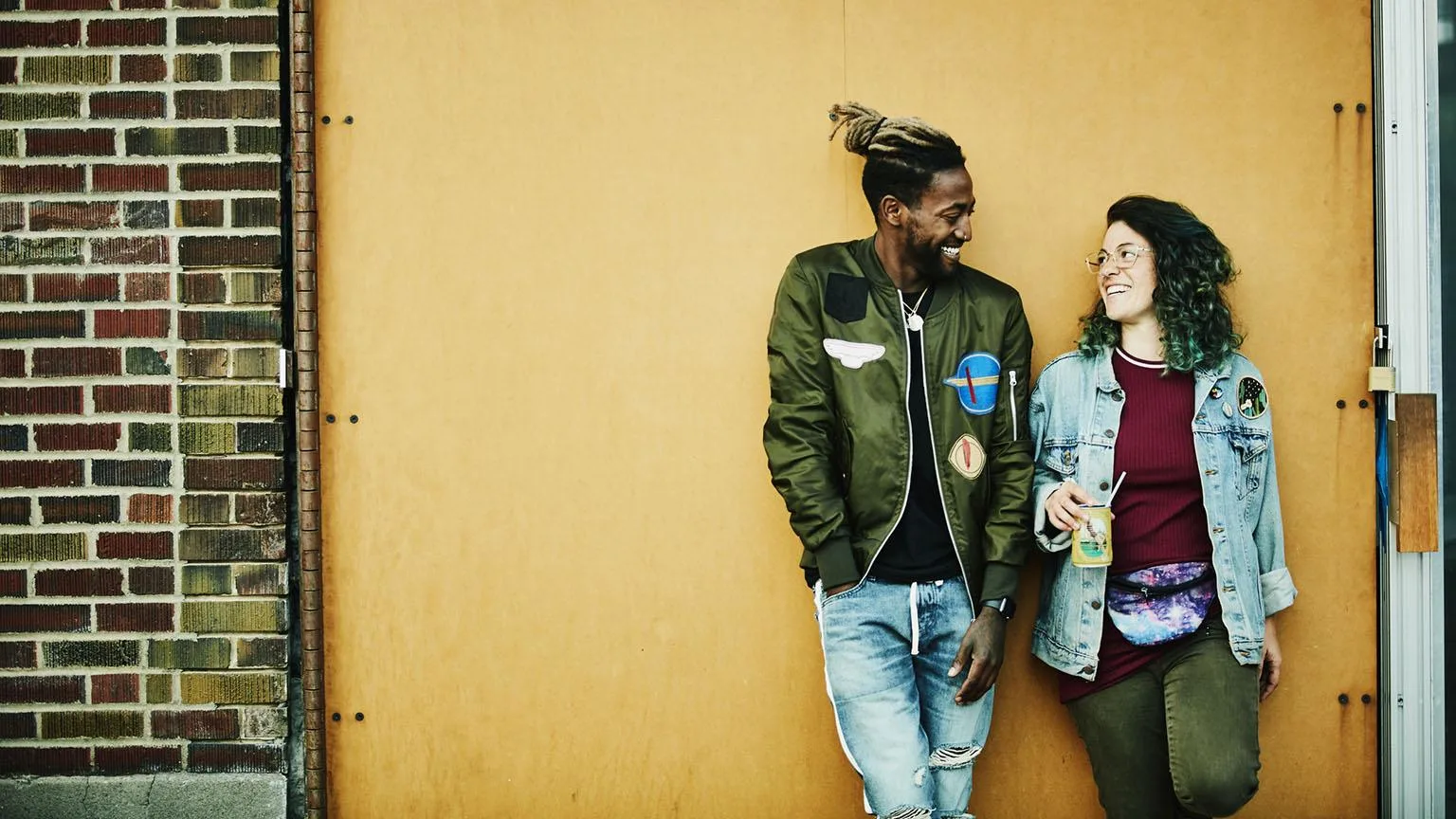 Image: Getty Images Young man and woman lean against a wall.