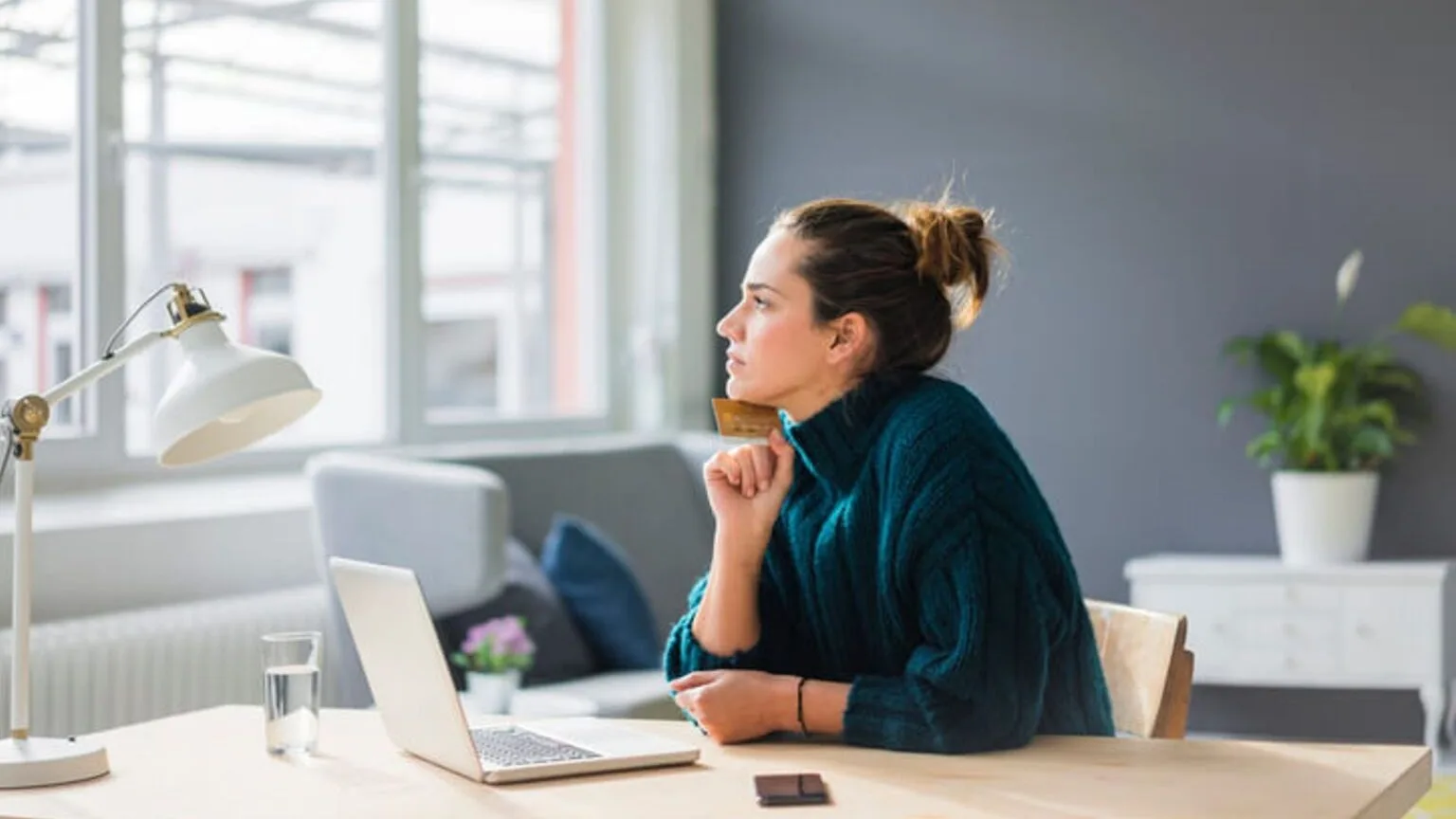 Image: Getty Images lady sitting at computer looking out window