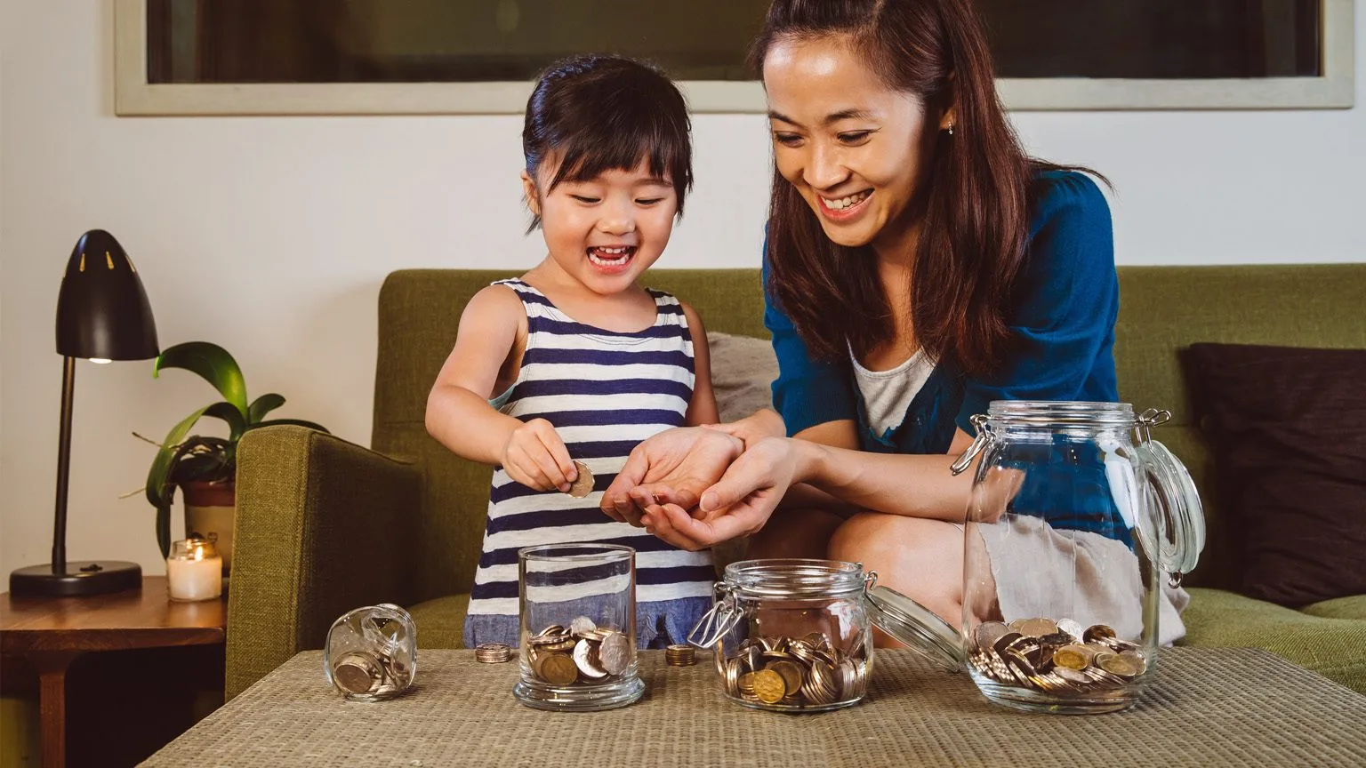 Image: Getty Images Young girl learning about savings with mum
