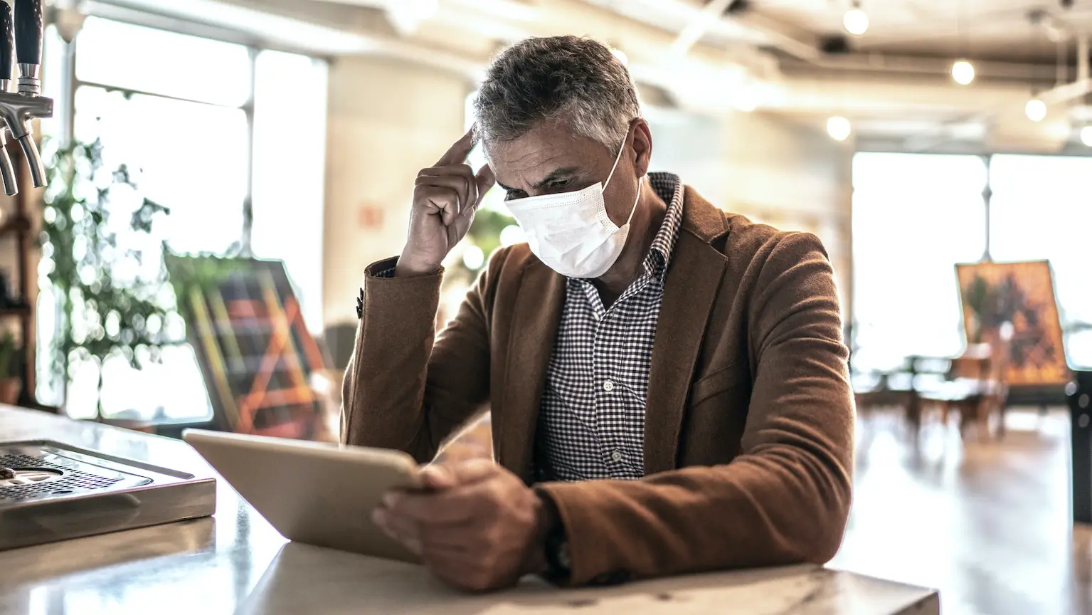 Image: Getty Images Homme avec masque de protection qui gère un compte bancaire en ligne
