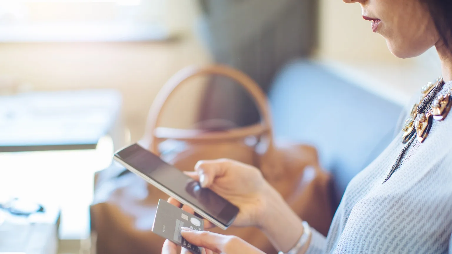 Image: Getty Images Woman loking at phone and card