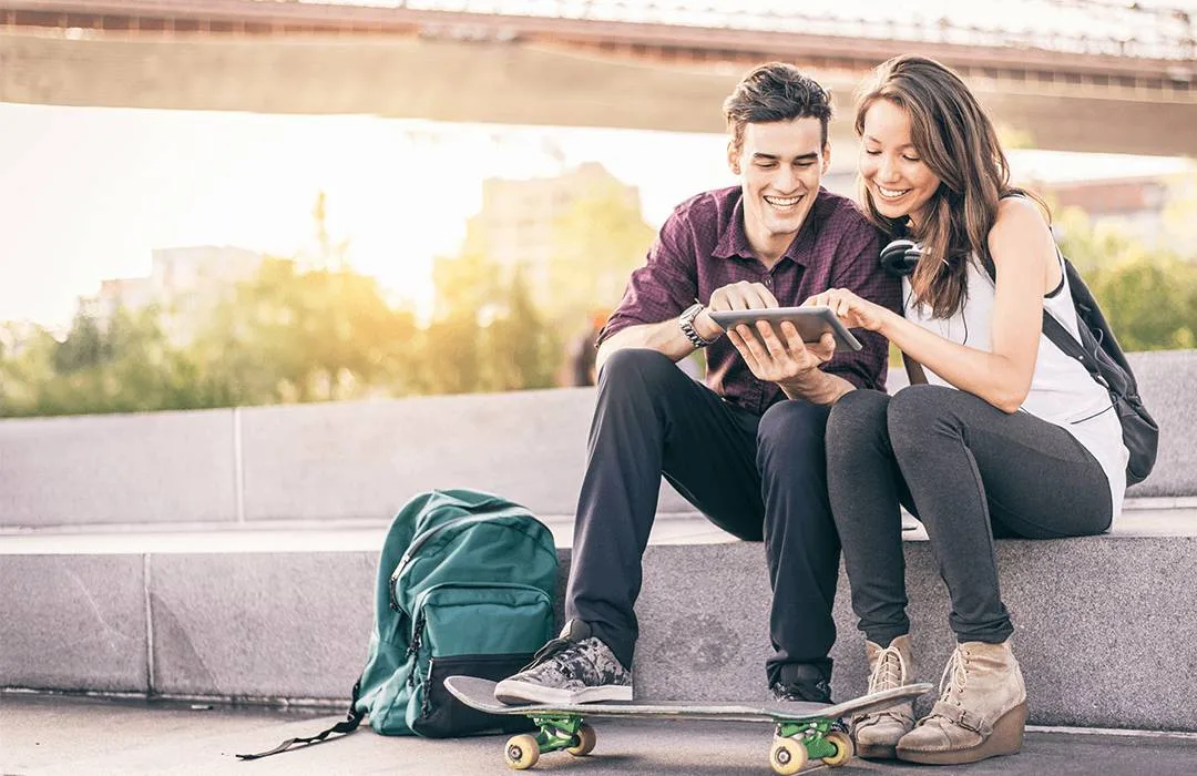 A couple sat together looking at a tablet.