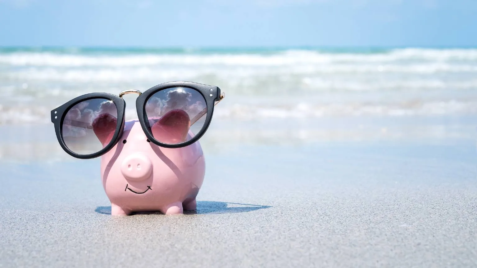 Image: Getty Images Piggy bank with sunglasses on the beach