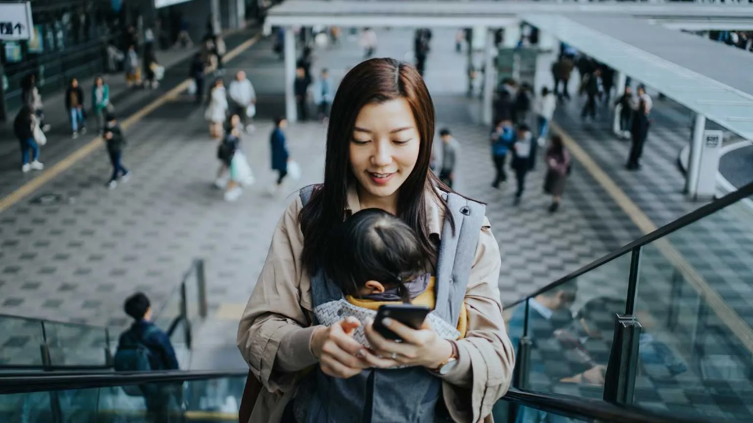 Image: Getty Images Woman on her phone with a baby