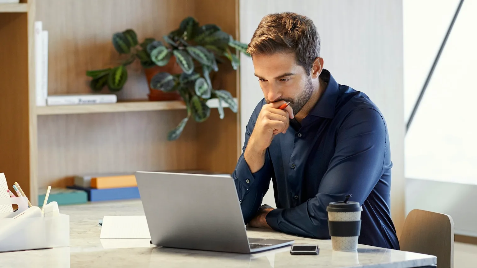 Image: Getty Images Serious mid adult professional looking at laptop. Confident businessman working at desk. He is concentrating in office.