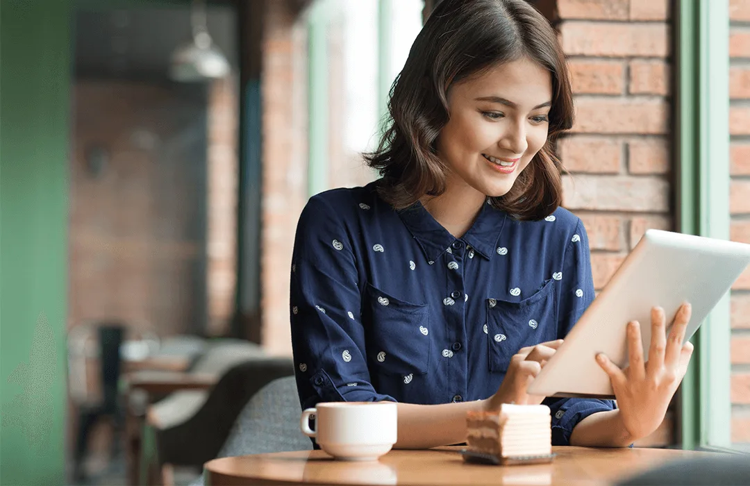 Image: Getty Images Young lady in cafe smiling at tablet